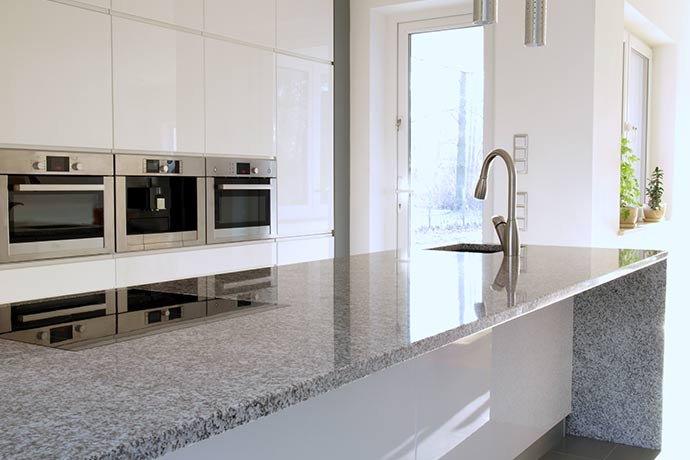 gray and black granite countertops in a modern, white kitchen